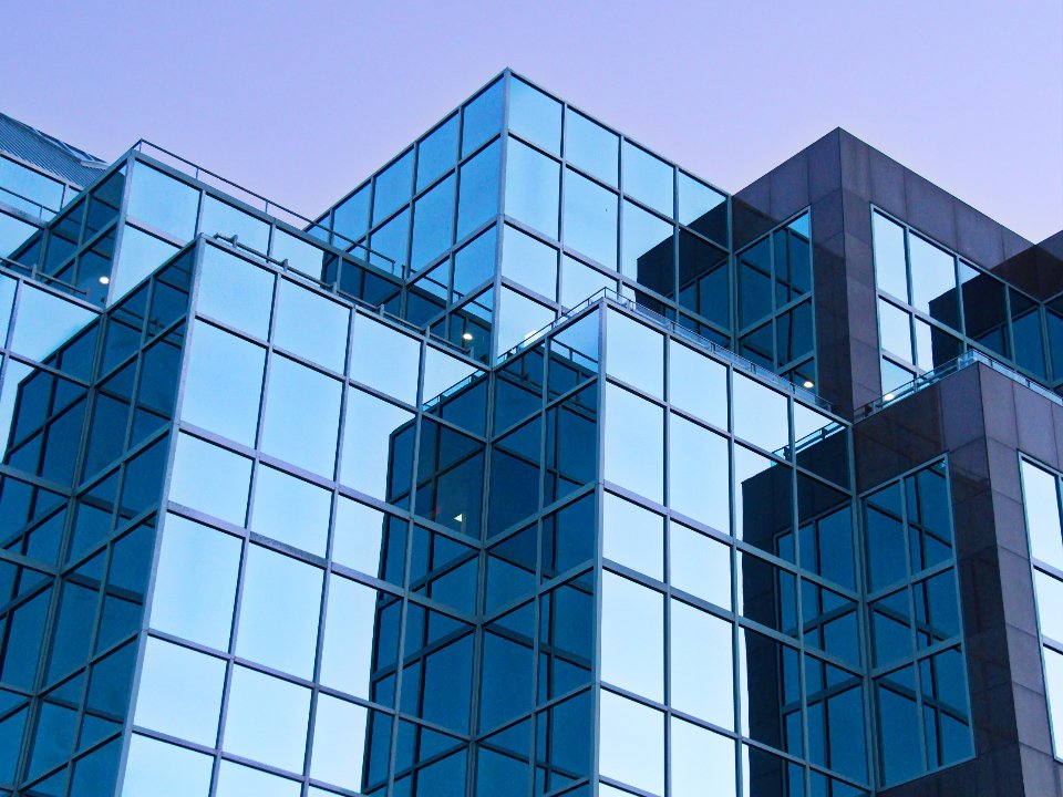 Angular blue glass facade of a modern office building against a clear sky